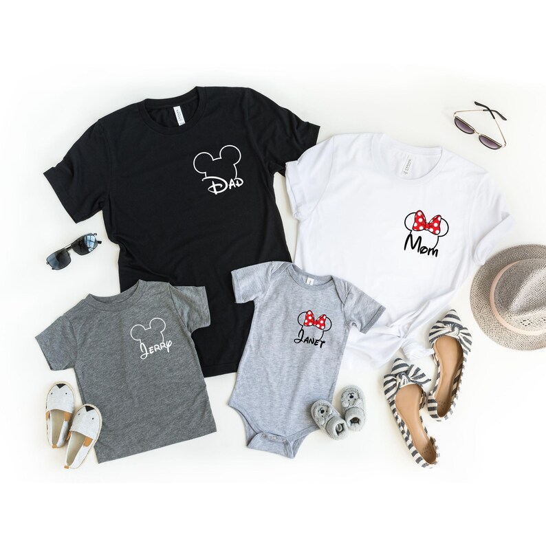 May include: Four matching family t-shirts and a onesie. The black shirt says "Dad", the white shirt says "Mom", the gray shirt says "Jerry", and the gray onesie says "Janet". Each shirt and onesie has a Mickey Mouse head design.