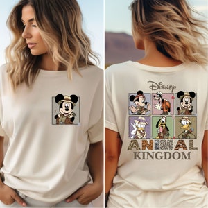 Pu&ograve; includere: Una maglietta bianca con un'immagine di Topolino vestito da esploratore sul davanti e un'immagine di Topolino e i suoi amici vestiti da esploratori sul retro. Il testo "Disney Animal Kingdom" &egrave; stampato sotto l'immagine sul retro.