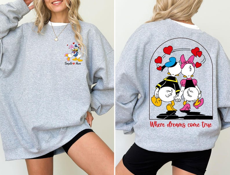 May include: Gray sweatshirt with a cartoon image of Donald and Daisy Duck holding hands in a heart-shaped archway with the text "Where dreams come true". The front of the sweatshirt has a smaller image of Donald and Daisy Duck with the text "Sequoia + Alex".