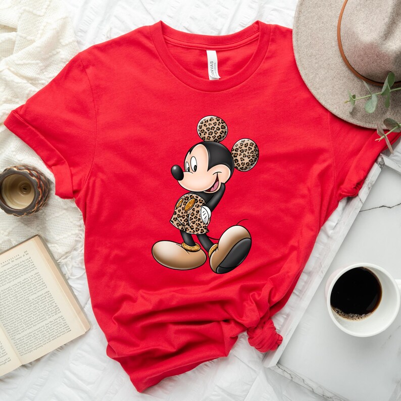 Op de afbeelding: Rood T-shirt met een cartoon afbeelding van Mickey Mouse met een luipaardprint broek en oren.