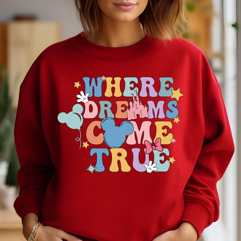 May include: Red sweatshirt with a colorful graphic that says "Where Dreams Come True" with Mickey Mouse ears, a castle, and stars.
