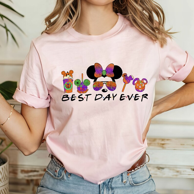 May include: Pink t-shirt with a graphic of Mickey Mouse and friends in Halloween costumes. The text "BEST DAY EVER" is printed below the graphic.