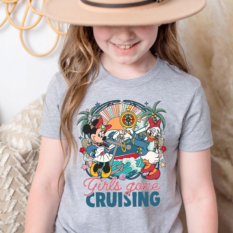 May include: A gray t-shirt with a colorful graphic of Mickey Mouse and Minnie Mouse dressed as sailors on a ship. The text "Girls gone cruising" is printed below the graphic.