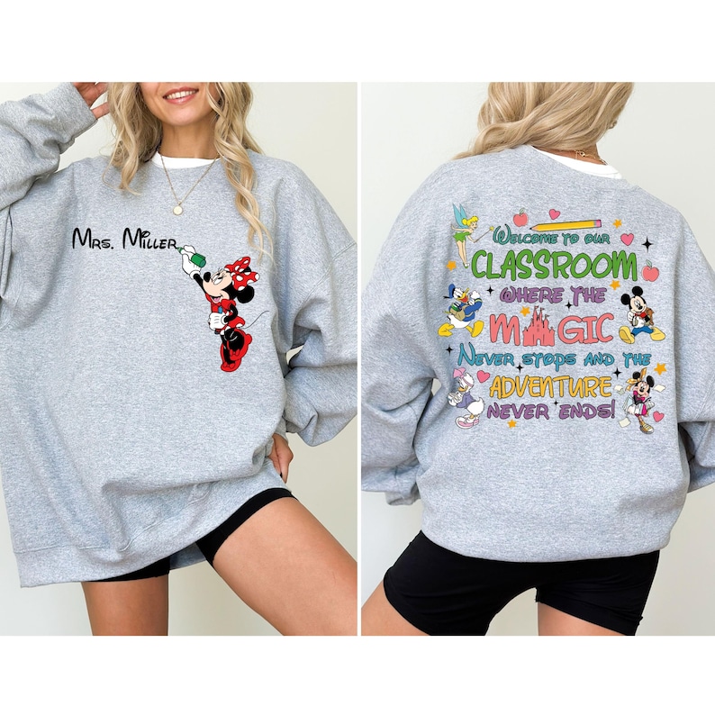 May include: Gray sweatshirt with a Mickey Mouse character and the text "Mrs. Miller" on the front. The back of the sweatshirt has a colorful design with Mickey Mouse, Minnie Mouse, Donald Duck, and Tinkerbell characters. The text on the back reads "Welcome to our classroom where the magic never stops and the adventure never ends!"