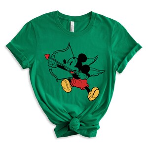 May include: Green t-shirt featuring a cartoon image of Mickey Mouse dressed as Cupid, holding a bow and arrow with a heart on the arrowhead.