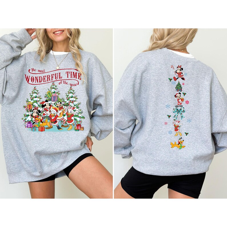 Puede incluir: Sudadera gris claro con un dise&ntilde;o festivo de Disney. La parte delantera muestra el texto "the most WONDERFUL TIME of the year" sobre una escena navide&ntilde;a con personajes. La parte trasera tiene un patr&oacute;n vertical de personajes de Disney y elementos festivos.