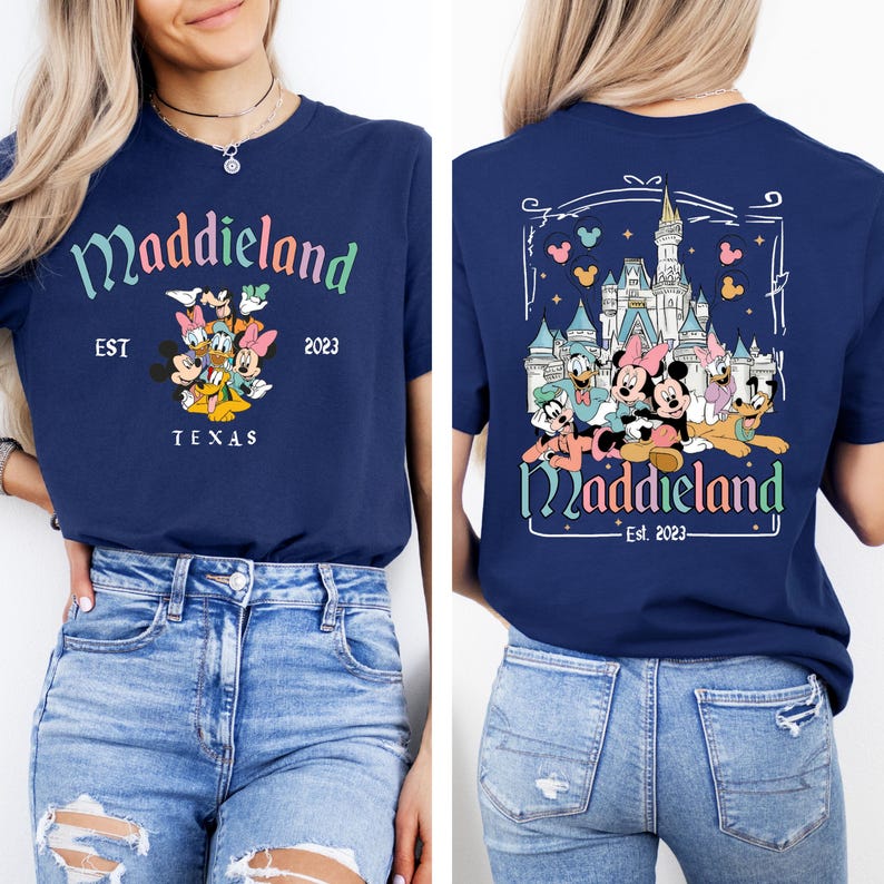 May include: A navy blue t-shirt with a graphic of Mickey Mouse and friends in front of Cinderella's Castle. The text "Maddieland Est. 2023" is printed on the shirt.