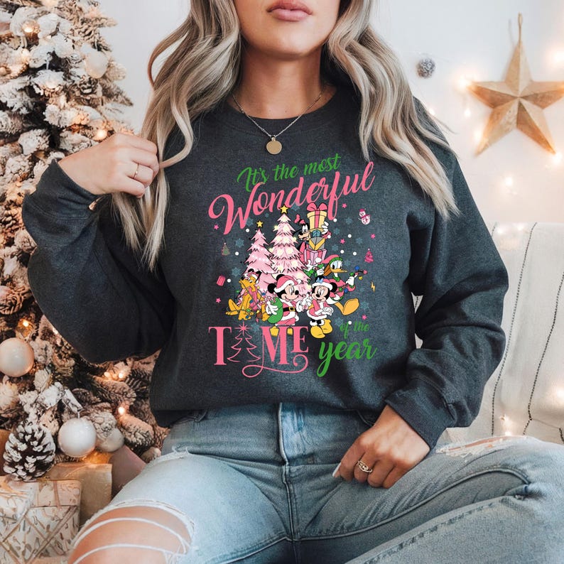 May include: A gray sweatshirt with a pink and green Christmas design featuring Mickey Mouse and friends. The text on the sweatshirt reads "It's the most Wonderful Time of the Year".