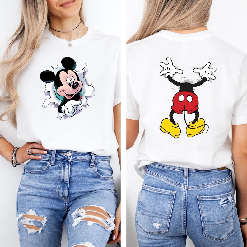 Puede incluir: Camiseta blanca con un dise&ntilde;o de Mickey Mouse. La parte delantera muestra a Mickey rompiendo un efecto rasgado, mientras que la parte trasera muestra la pose ic&oacute;nica de Mickey. La camiseta se combina con unos vaqueros azules.