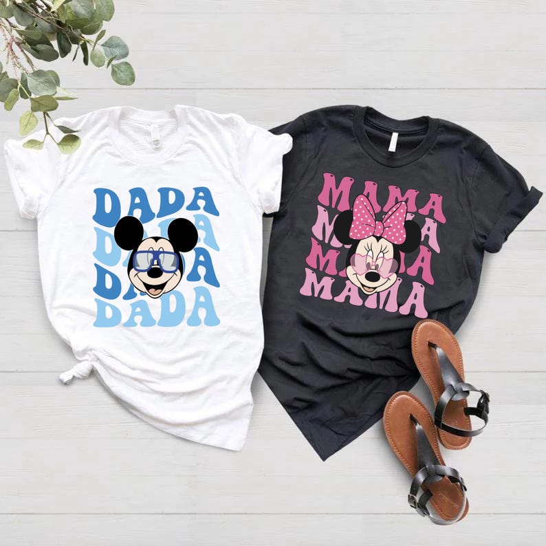 May include: Two white t-shirts with a black and white Mickey Mouse graphic and the text "DADA" in blue and white. Two black t-shirts with a pink and white Minnie Mouse graphic and the text "MAMA" in pink and white.