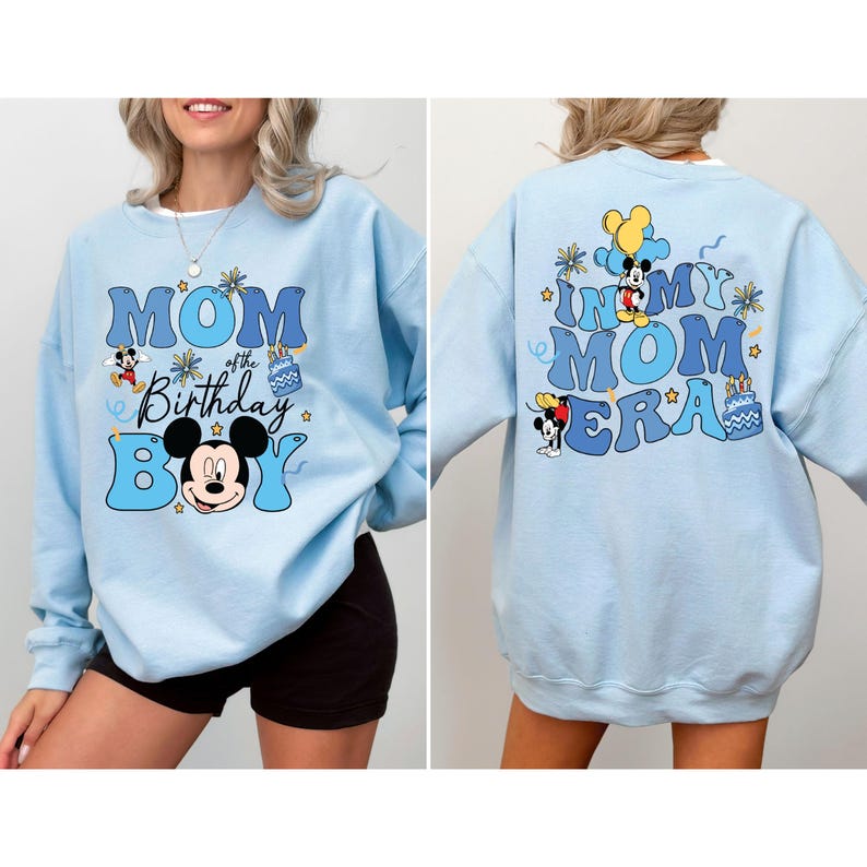 K&ouml;nnte beinhalten: Hellblauer Pullover mit einem grafischen Aufdruck von Mickey Mouse und dem Text "Mom of the Birthday Boy" auf der Vorderseite und "In My Mom Era" auf der R&uuml;ckseite.
