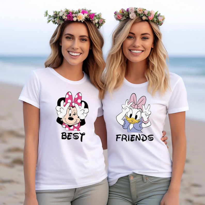 Może przedstawiać: Dwie białe koszulki z nadrukiem postaci z kresk&oacute;wek: Minnie Mouse i Daisy Duck. Koszulka z Minnie Mouse ma napis "Best", a koszulka z Daisy Duck ma napis "Friends".