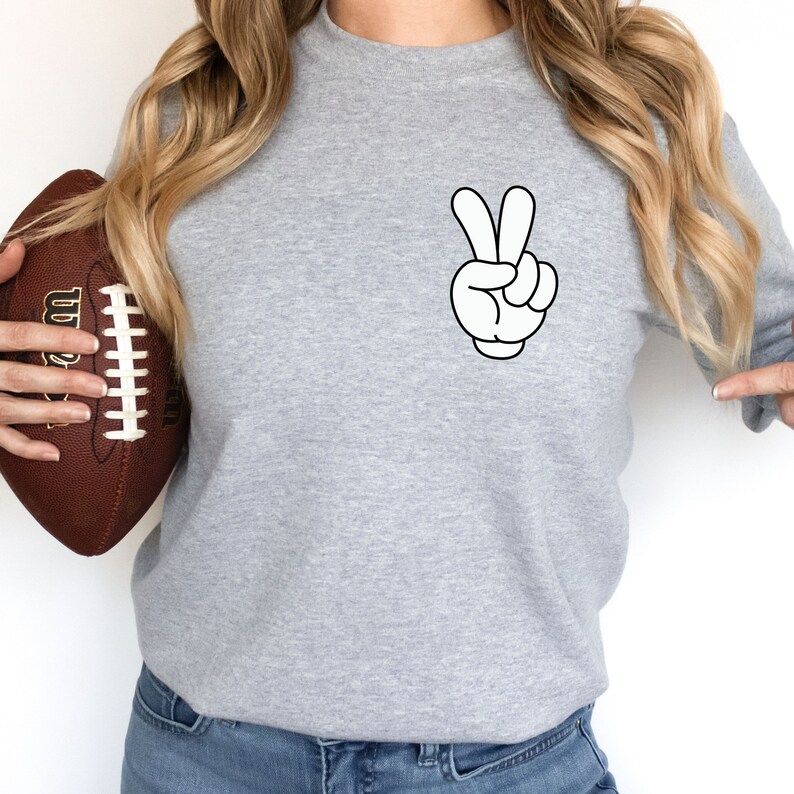 May include: A gray sweatshirt with a white cartoon hand making a peace sign on the front.