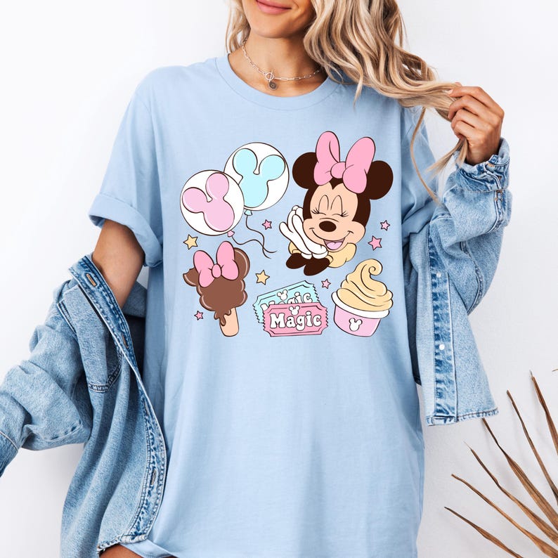 May include: Light blue t-shirt with a graphic of Minnie Mouse holding balloons, a Mickey Mouse ice cream bar, and a ticket that says "Magic" with a Mickey Mouse head.