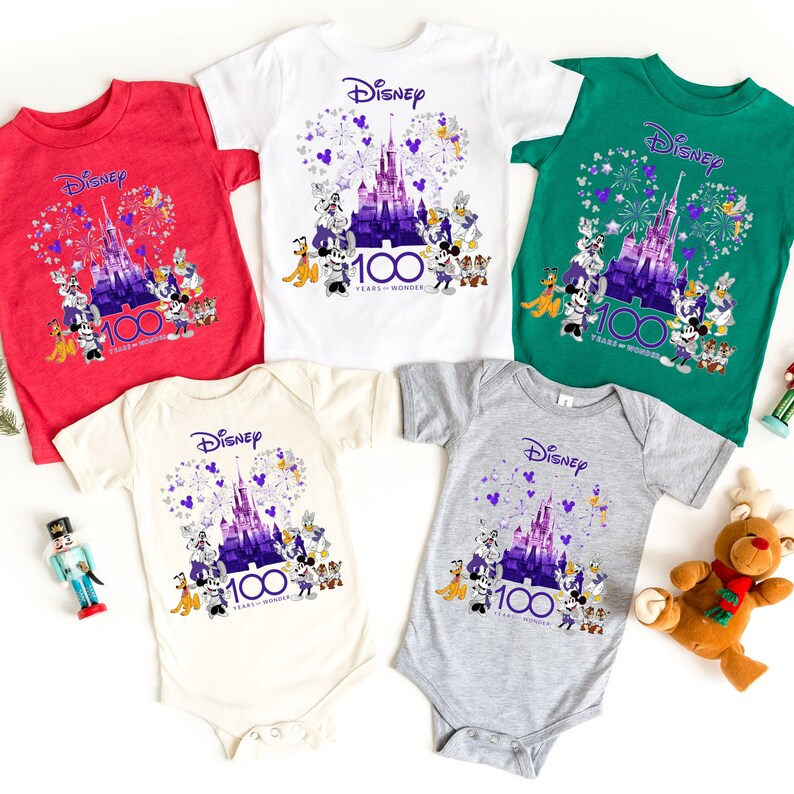 May include: Five different t-shirts featuring a purple and white illustration of Cinderella's castle with fireworks and Disney characters. The text "Disney 100 Years of Wonder" is printed on each shirt.