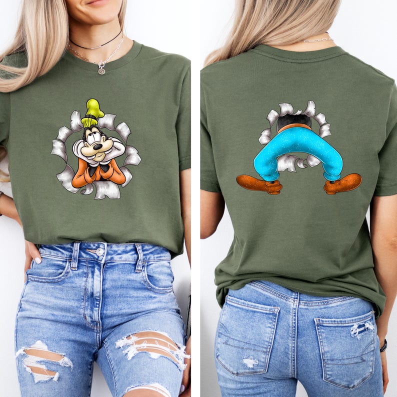 K&ouml;nnte beinhalten: Olivgr&uuml;nes T-Shirt mit einem Cartoon-Charakter-Design. Die Vorderseite zeigt die Figur, die durch ein zerrissenes Loch blickt, und die R&uuml;ckseite zeigt die Beine und F&uuml;&szlig;e der Figur. Das Design enth&auml;lt orange, gelbe, blaue und braune Akzente.