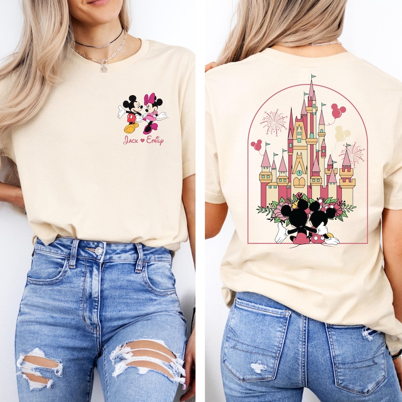 K&ouml;nnte beinhalten: Ein hellbeiges T-Shirt mit einem Motiv von Mickey und Minnie Mouse auf der Vorderseite und einem Motiv von Schloss Aschenputtel mit Mickey und Minnie Mouse auf der R&uuml;ckseite. Der Text "Jack & Emily" ist unter dem Mickey- und Minnie-Mouse-Motiv auf der Vorderseite des Shirts gedruckt.