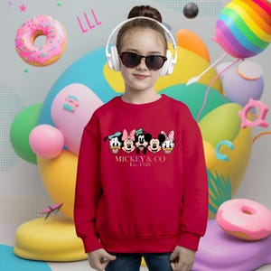 May include: Red sweatshirt with a graphic of Mickey Mouse and friends. The text "Mickey & Co. Est. 1928" is printed below the graphic.