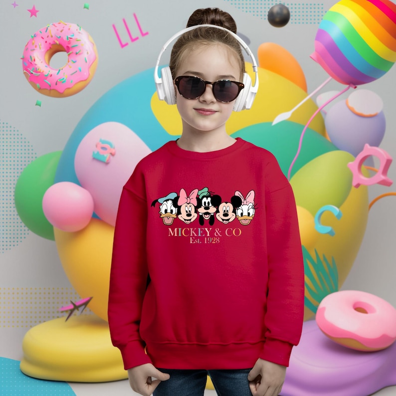 May include: Red sweatshirt with a graphic of Mickey Mouse and friends. The text "Mickey & Co. Est. 1928" is printed below the graphic.