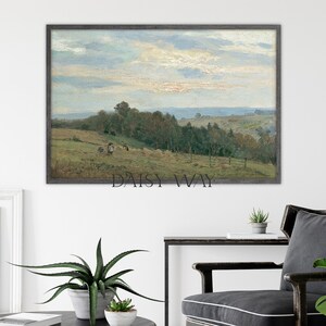 May include: A framed landscape painting depicting a rural scene with a field, trees, and a cloudy sky. The painting is in a gray frame and is hanging on a white wall.