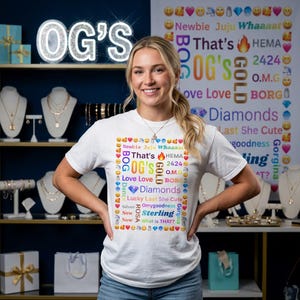 May include: A white short-sleeved t-shirt featuring a central square graphic composed of colorful text and emojis. The text includes phrases like OG's, Gold, Diamonds, and Sterling, surrounded by a border of various emojis on a white background.