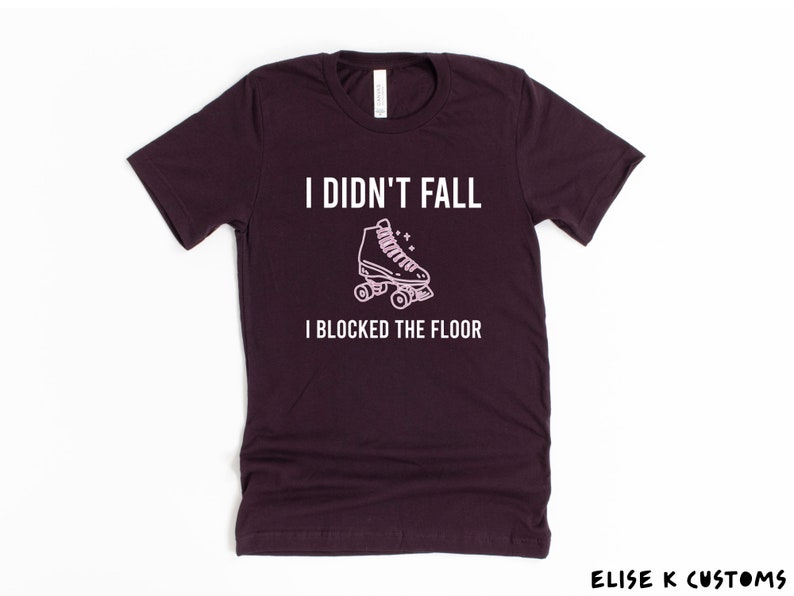 K&ouml;nnte beinhalten: Ein dunkelviolettes T-Shirt mit dem Text "Ich bin nicht gefallen, ich habe den Boden blockiert" und einer rosa Umrandung einer Rollschuh.