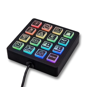 Puede incluir: Un panel de control rectangular negro con 16 botones. Cada botón tiene un símbolo diferente y está iluminado con un color diferente. Los símbolos incluyen un volante, un camión, una bocina, una luz, un limpiaparabrisas, un freno de estacionamiento y una flecha. El panel está conectado a un cable negro.