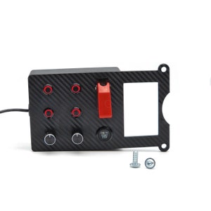 Könnte beinhalten: Schwarzes Carbonfaser-Panel mit sechs roten Kippschaltern, zwei schwarzen Knöpfen und einem roten Kippschalter. Das Panel hat außerdem einen rechteckigen Ausschnitt und einen roten Knopf mit der Aufschrift "Engine Start Stop". Zwei silberne Schrauben sind im Lieferumfang enthalten.