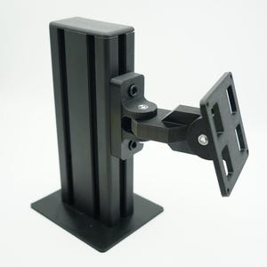 May include: Black metal monitor arm with a swivel joint and a square base. The arm is attached to a vertical black metal pole.