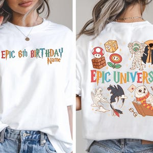 May include: White t-shirt with colorful text and graphics. The front says "Epic 6th Birthday" with a space for a name. The back features "Epic Universe" and cartoon illustrations of a mushroom, a mummy, a dragon, and an owl.