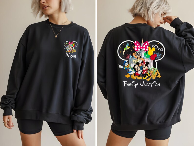 May include: Black sweatshirt featuring a colorful Disney family graphic on the front and back. The front displays "Mom" and the back shows "Family Vacation 2020" with Mickey, Minnie, Donald, and other characters. A comfortable, casual style.