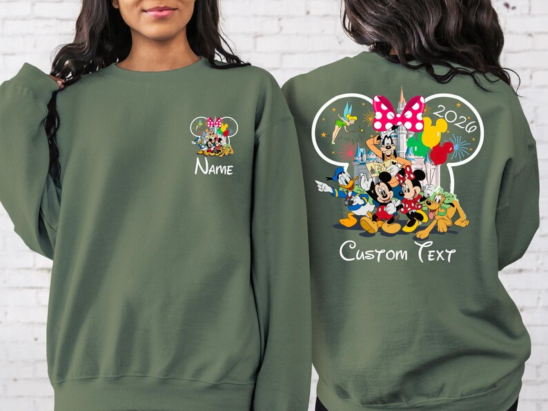 May include: Olive green sweatshirt featuring Disney characters Mickey, Minnie, Donald, Goofy, and Pluto. The front has a small graphic with the word "Name". The back has a larger graphic with "2026" and "Custom Text".