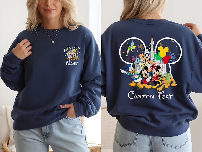 May include: Navy blue sweatshirt featuring a Disney-themed design. The front displays a Mickey Mouse ear outline with Disney characters and the word "Name". The back showcases a larger design with characters, fireworks, and the text "Custom Text".