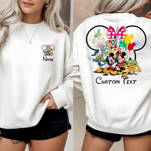 May include: White sweatshirt featuring a Mickey Mouse design with the text "Name" on the front and a larger Mickey Mouse design on the back with the text "Custom Text". The back design includes Mickey, Minnie, Donald, Goofy, and other characters.