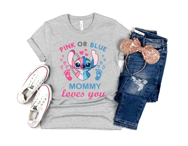 Puede incluir: Camiseta gris con un personaje Stitch azul y rosa sosteniendo un pie de beb&eacute; rosa y azul. El texto "Pink or Blue Mommy loves you" est&aacute; impreso en la camiseta.