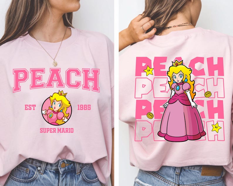 May include: Light pink t-shirt featuring the word "PEACH" in large pink block letters. The front of the shirt has a circular graphic of Princess Peach from Super Mario. The back of the shirt has a larger graphic of Princess Peach.