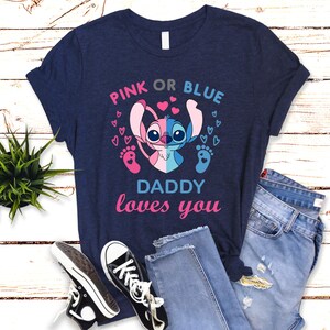 Puede incluir: Una camiseta azul marino con un personaje Stitch rosa y azul con el texto "Pink or Blue Daddy loves you".