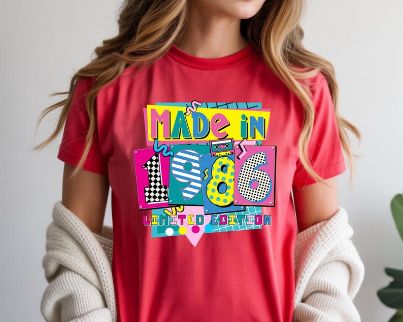 May include: A red t-shirt with a colorful graphic that says "MADE IN 1986 LIMITED EDITION." The graphic has a retro 80s design with bright colors and geometric shapes. The shirt is short-sleeved.