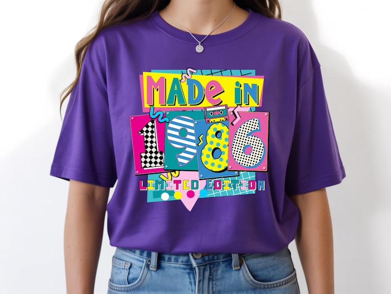 May include: A purple t-shirt with a colorful graphic design that says "MADE IN 1986 LIMITED EDITION." The design features the numbers 1, 9, and 6 in different patterns and colors, with a cassette tape illustration.