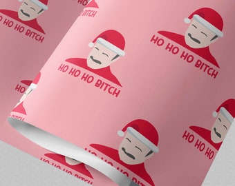 May include: Wrapping paper with a repeating pattern on a light pink background. The design features a cartoon illustration of a person wearing a red Santa hat and a red shirt, with the text HO HO HO BITCH printed in red below the illustration.