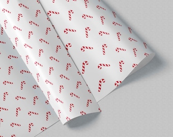 May include: A roll of white wrapping paper featuring a repeating pattern of small red and white striped candy canes. The paper is displayed in a partially unrolled position, showcasing the consistent graphic design across the smooth surface.