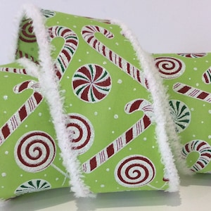 May include: A green ribbon with a repeating pattern of red and white candy canes and peppermint sweets. The ribbon is trimmed with white faux fur. This festive ribbon is ideal for Christmas decorations and gift wrapping.