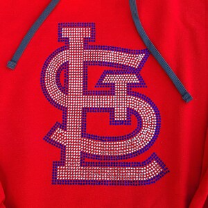 May include: Red hooded sweatshirt with a large, white and blue rhinestone 'LS' logo on the front.