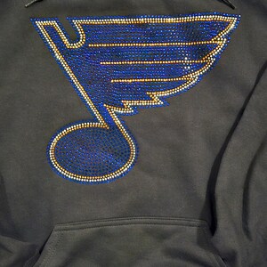 May include: Black hoodie with a blue and gold rhinestone St. Louis Blues logo on the front.