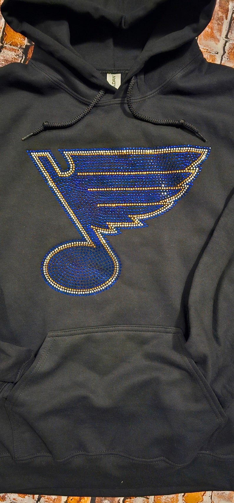 May include: Black hoodie with a blue and gold rhinestone St. Louis Blues logo on the front.