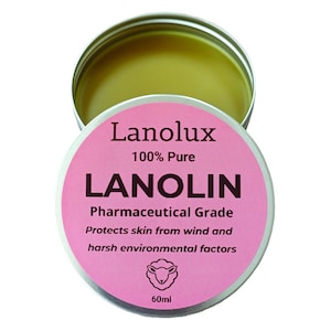 May include: A pink and silver tin of Lanolux 100% Pure Lanolin, Pharmaceutical Grade. The tin is labelled with the product name, purity, grade, and a description of its use: "Protects skin from wind and harsh environmental factors". A small sheep icon is also included on the label. The tin contains 60 ml of lanolin.