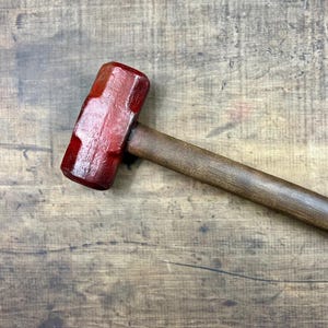 Può includere: Un martello demolitore rosso e marrone con manico in legno.