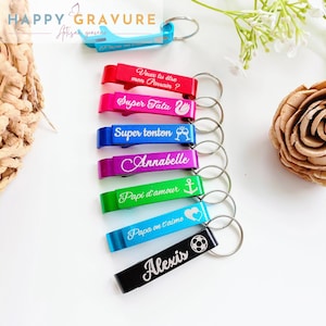 Peut inclure: Un ensemble de huit ouvre-bouteilles colorés avec des porte-clés. Chaque ouvre-bouteille porte une inscription différente, notamment "Super Tata", "Super tonton", "Annabelle", "Papi d'amour", "Papa on t'aime" et "Alexis".