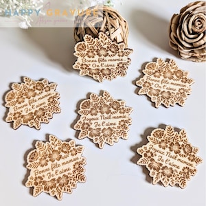 Puede incluir: Una colección de adornos florales de madera cortados con láser. Cada adorno presenta un diseño floral y texto en francés, incluyendo "Bonne fête mamie. Je t'aime" y "Joyeux Noël mamie. Je t'aime".