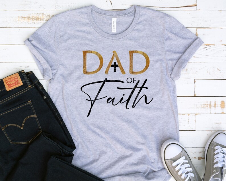 May include: A gray t-shirt with the text "DAD of Faith" in gold and black lettering. The word "DAD" has a cross in the middle of the "A".